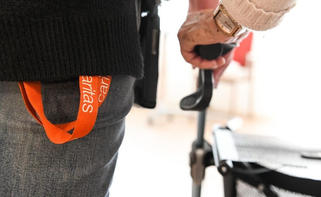 Caritas-Fachkraft unterstützt ältere Frau mit dem Rollator